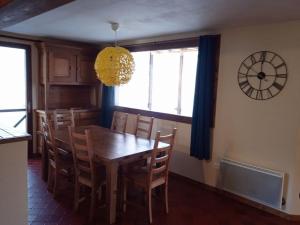 a dining room with a table and chairs and a clock at L'Aussoyenne in Aussois +2 photos