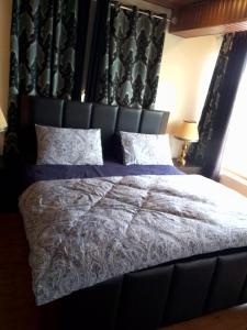 a bedroom with a large bed with a black headboard at AK Homes in Rāwāt +10 photos