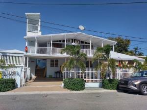 a white house with a car parked in front of it at Cabana Playa Santa Apto C Piscinas Solar Energy in Guanica
