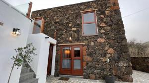 a stone house with a wooden door and windows at Casa Pilmar in Las Rosas