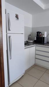 een witte koelkast in een keuken met witte kasten bij SILVESTRE - Departamento in Cordoba +5 foto's