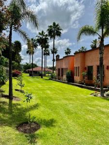 a green yard with palm trees and a building at Rancho La Querencia in Tala