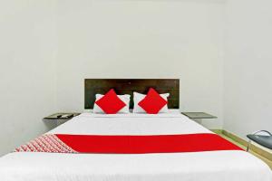 a red and white bed with red pillows on it at Hotel O Meridian Grand in Shamshabad