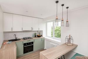 a kitchen with white cabinets and a wooden table at Sunshine apartamentai in Alytus