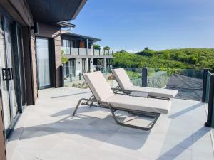 2 weiße Sessel auf einer Terrasse in der Unterkunft Tamarind Hills Resort & Villas in Johnsons Point