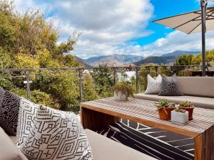 a patio with a table and chairs on a balcony at Calais Guest House in Franschhoek