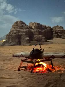 a pot on top of a fire in the desert at Wadi Rum Luxury Hamad & Jeep Tours in Wadi Rum