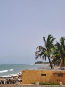 a beach with a building and palm trees and the ocean at Senebreizh in Somone