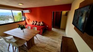 una camera con letto rosso, tavolo e finestra di La Moradita Villa Carlos Paz a Villa Carlos Paz