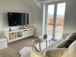 a white living room with a tv and a couch at Envolée des rêves - Terrasse - Parking privé in Wintzenheim