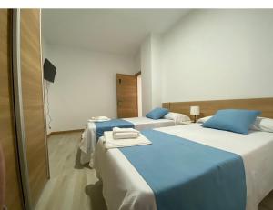 two beds in a room with blue and white at Hostal el Olivo in Mora