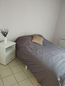 a bed with a pillow and a night stand in a room at appartement entier 2 chambres in Mantes-la-Ville