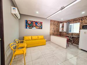 a living room with a yellow couch and a kitchen at Pousada Cheiro do Mar in Porto De Galinhas