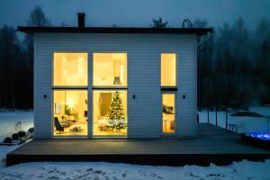 a house with large windows and a christmas tree at Villa Nightsky -private location, sauna and jacuzzi in Rovaniemi