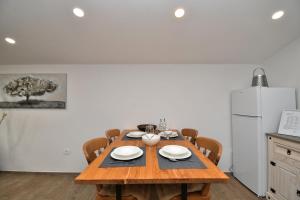 a dining room table with chairs and a white refrigerator at Apartments Plomin in Plomin +39 photos