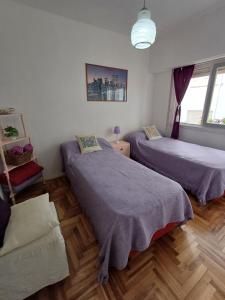 two beds in a room with wooden floors at DESCANSO IDEAL III Casino, playa y shopping in Mar del Plata