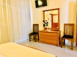 a bedroom with a dresser and two chairs and a mirror at Ama Villa Negombo in Negombo