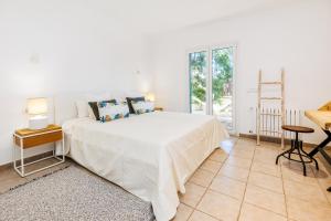 a white bedroom with a bed and a table at Casa Colom in Portocolom
