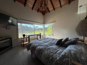 une chambre avec un lit et une grande fenêtre dans l'établissement Carilo para 10, frente al golf con Pileta Climatizada!, à Carilo