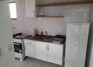 a kitchen with white cabinets and a sink and a stove at Flat Confortável in Campos dos Goytacazes +7 photos