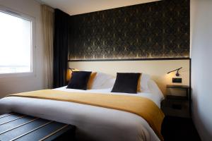 una camera da letto con un letto grande e una finestra di Hôtel & Résidence Octel a Portet-sur-Garonne