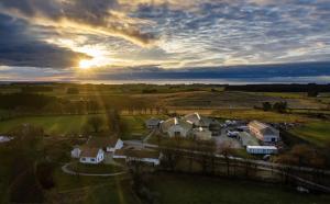 una casa in un campo con il tramonto sullo sfondo di Leilighet i Nærbø sentrum a Narbø