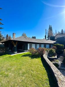 a house with a stone fence in the yard at TEROTERO Lake Hostel - Habitación Mascardi in San Carlos de Bariloche