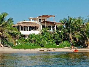 a house on the beach with a person in the water at Villa Queridoro Mahahual in Mahahual