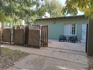 a fence in front of a house with two chairs at Casa Ruca Lawen in Sierra de la Ventana +2 photos