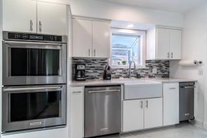 a kitchen with white cabinets and stainless steel appliances at Oceanfront Retreat 2 Homes for 29-Guests in Corpus Christi