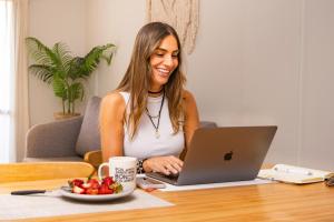 a woman sitting at a table with a laptop computer at Alisos 5 A con cochera in San Miguel de Tucumán