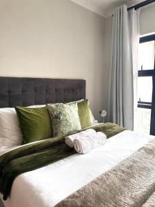 un letto con cuscini verdi e bianchi e una finestra di Serenity@TheBlyde a Pretoria