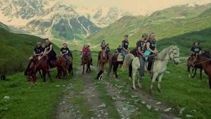a group of people riding horses in the mountains at Ushguli Hotel Riho in Ushguli