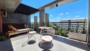 een patio met 2 stoelen en een bank op een balkon bij 3 Personas - Balcon, Wifi & Cafe in Santiago del Estero