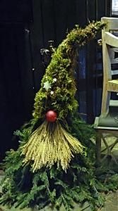 a wreath with a plant and a broom next to a chair at Bungalow direkt am See, mit eigenem Boot in Roding