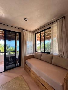 a living room with a couch and windows at Villa Queridoro Mahahual in Mahahual +65 photos