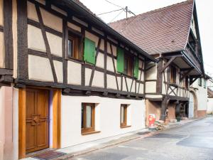 ヴィンツェンハイムにあるla petite maisonの緑窓と茶色の扉のある古い建物