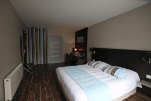 a bedroom with a large bed and a desk at Hôtel Le Cheval Blanc in Quend-Plage