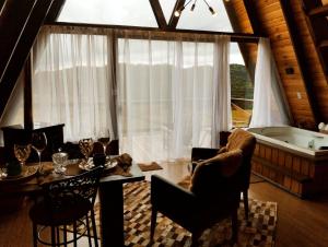 a living room with a table and a bath tub at Chalés Corucacas in Cambará