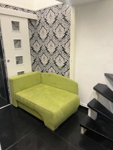 ein grünes Sofa in einem Zimmer mit einer Wand in der Unterkunft Fashion street mini apartment in Budapest
