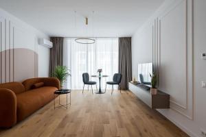 a living room with a couch and a table and chairs at Orange Luxury King bed Apartment, bussiness, leisure in One Cotroceni in Bucharest
