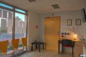 Hotel A4 Młyński Staw Autostarada A4 Opole في Rzędziwciowice: غرفة انتظار مع كراسي وطاولة وباب