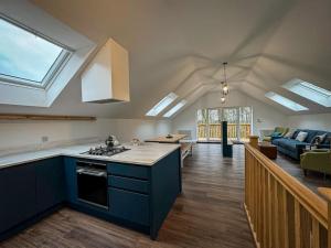 a kitchen with blue cabinets and a living room at Derwent, woodland lodge with hot tub for 6 in Oakamoor