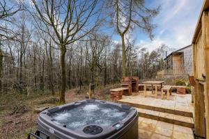 a hot tub on a patio with a picnic table at Derwent, woodland lodge with hot tub for 6 in Oakamoor