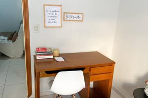 a wooden desk with a white chair in a room at Varanda, TV 50, elevador, no Centro, garagem paga in Viçosa