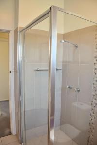 a shower with a glass door in a bathroom at Spencer's Cottage - Bring your own linen. in South West Rocks +12 photos