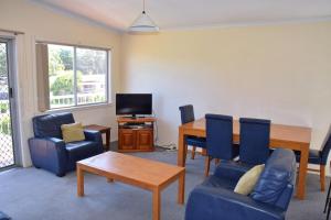 a living room with a table and chairs and a tv at Spencer's Cottage - Bring your own linen. in South West Rocks
