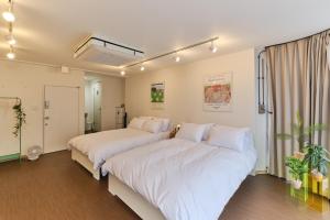 two beds in a room with white sheets at Kaikai House - Art, Design & Family in Shibuya in Tokyo