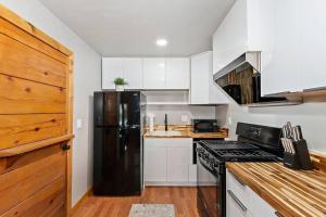 eine Küche mit einem schwarzen Kühlschrank und weißen Schränken in der Unterkunft NEW Cozy Coy Cabin with Hot Tub & AC in Big Bear City + 5 Fotos