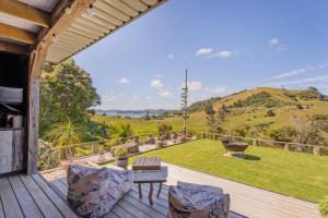 un patio avec une table et des chaises sur une terrasse dans l'établissement Hosts on the Coast Bayview Sanctuary, à Whitianga